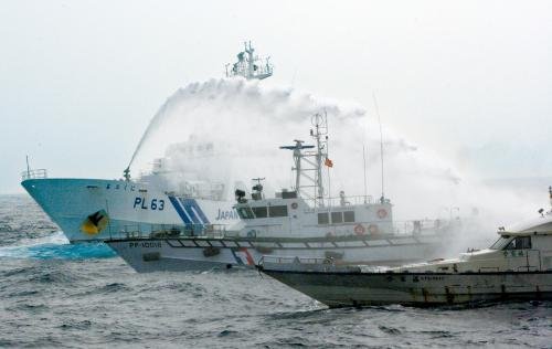 臺(tái)灣“海巡署”的巡邏船（中）在掩護(hù)保釣船“全家?！碧?hào)（右）躲避日本海上保安廳巡視船的水炮攻擊。