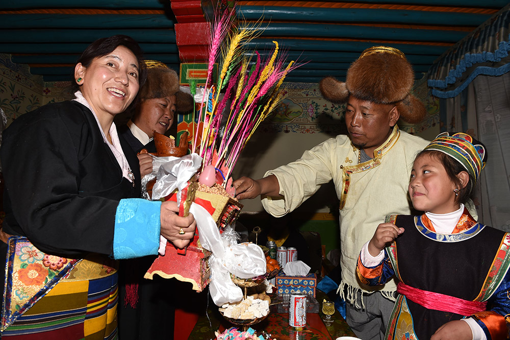 2月27日，拉薩市城關(guān)區(qū)阿壩林卡社區(qū)居民央拉（左）向鄰居敬獻(xiàn)“切瑪”。